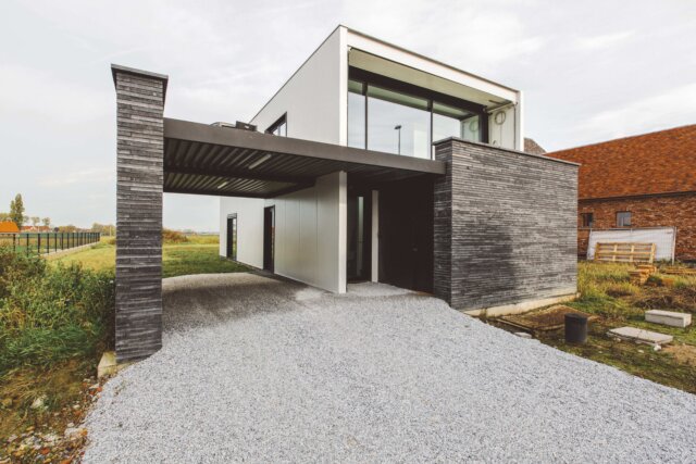 moderne passiefwoning met carport in donker steen en witte gevel, gebouwd in staal